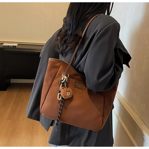 Detail der braunen matten Shopper-Tasche mit Lederetikett und Plüschbär-Anhänger