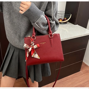 Detail of red pebbled leather tote bag with gold ring hardware and silk scarf decor