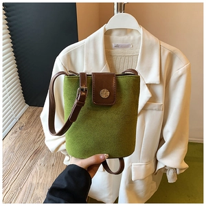 Detail of green suede bucket bag featuring brown leather flap and metal magnetic closure