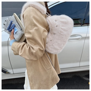 Detail of plush beige shoulder bag featuring star studs on a model in wool coat
