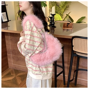 Detail of pink faux fur handbag with chunky silver ball chain strap on wooden bar
