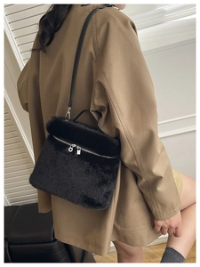 Détail du sac seau en fausse fourrure noire avec fermeture éclair argentée et cuir