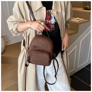 Detail showing the brown suede texture and golden metal zipper of the versatile backpack