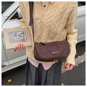 Close-up of a vintage coffee brown suede crescent bag worn with a casual outfit