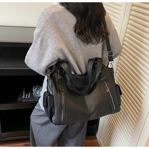 Detail of black lychee texture tote bag with side zippers and adjustable shoulder strap