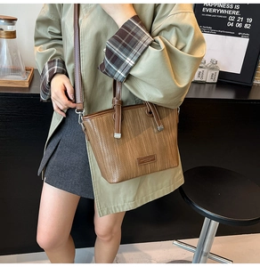 Detail of a brown woven pattern tote bag with logo patch and detachable shoulder strap