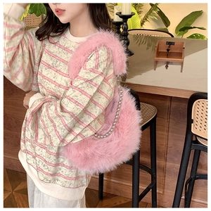 Pink fluffy faux fur shoulder bag with silver bead chain detail in cozy indoor setting