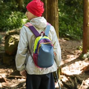 Outdoor lifestyle view of colorful hiking backpack worn by model in a forest setting