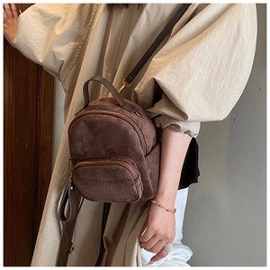 Detail view of mini brown faux suede backpack with adjustable straps on model