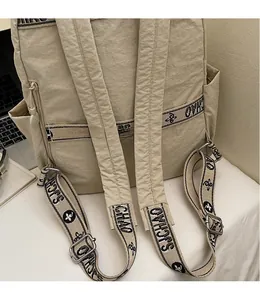 Detail of beige nylon backpack featuring wide jacquard straps and rear zipper pocket