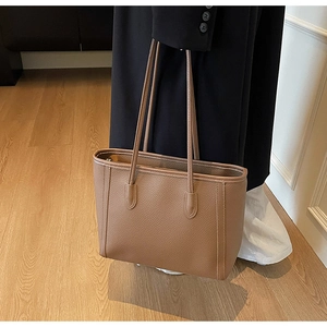 Close-up of brown litchi pattern leather tote bag with reinforced stitching and zipper