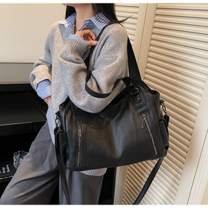 Detailed view of large black lychee leather tote bag with front zippers on a model