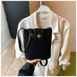 Detail of black matte bucket bag with leather accents and silver circular buckle buckle