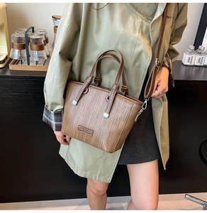 Detail of a brown woven texture bucket bag showing silver hardware and adjustable strap