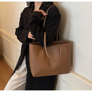Close-up of brown lychee-patterned leather tote bag with elegant decorative stitching