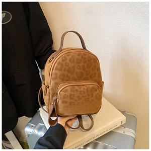 Close-up of a mini leopard print backpack with front pocket and zipper details
