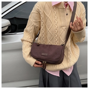 Detail of a vintage dark brown suede half-moon crossbody bag with metal zipper design