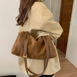 Détail d'un grand sac cabas en daim marron avec bretelles en cuir et boucle dorée