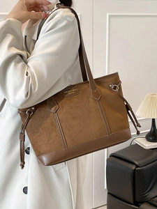 Retro brown suede tote bag with leather trim worn by a model in a modern interior