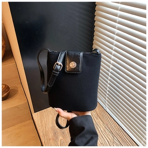 Close-up of black bucket bag featuring textured fabric and retro metal buckle detail