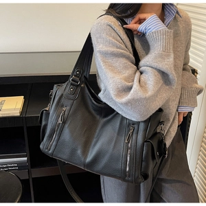 Detailed close-up of a large black tote bag with lychee texture and silver zipper accents