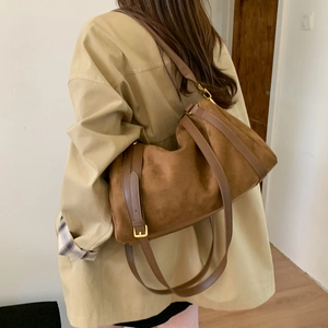 Sac polochon en daim marron avec garniture en cuir porté avec un trench-coat chic
