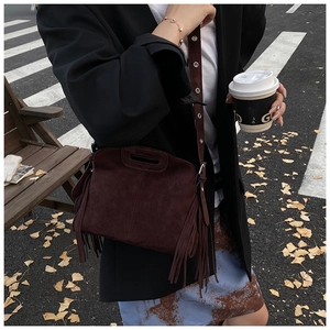 Detail view of burgundy frosted suede shoulder bag featuring stylish long side tassels