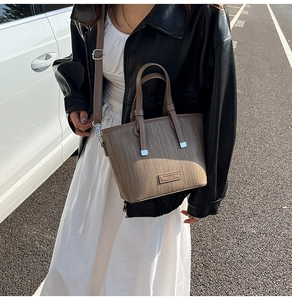 Detailed view of brown woven texture tote bag with metallic hardware and adjustable strap