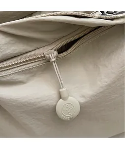 Detailed macro shot of a beige backpack zipper with an extended puller and logo