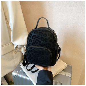 Detailed close-up of a mini leopard print backpack featuring dual-zipper compartments