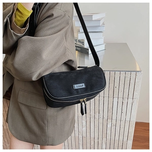 Detail of black matte half-moon crossbody bag with gold zippers and metal logo plate