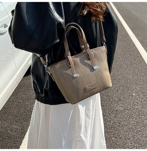 Close-up of brown textured leather bucket bag with metal buckle and fashion logo tag