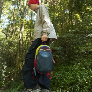 Outdoor hiking backpack with color-blocking design shown in a scenic forest environment