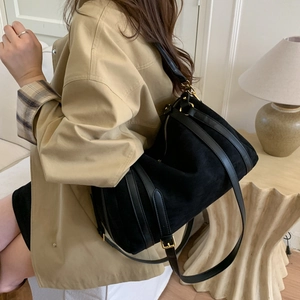 Détail d'un sac cabas en daim noir avec sangles en cuir et ferrures dorées