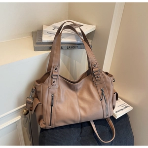 Detail of tan leather tote bag with lychee texture and symmetrical vertical zippers