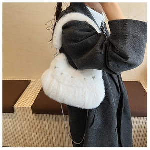 Detail of white plush shoulder bag with star rivets and chain strap on a model