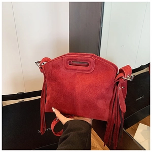 Macro detail of red frosted suede bag featuring long side tassels and bohemian style