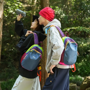 Outdoor shot showing side view of color-block hiking backpack with red mesh side pockets