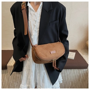 Detail of a brown suede crossbody bag with dual metal zippers and fine texture
