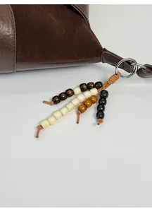 Detail of suede patchwork handbag with ethnic wood bead pendant in earthy tones