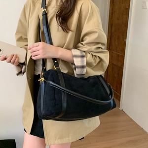 Vue détaillée d'un sac hobo en daim noir avec boucles dorées et bandoulière en cuir