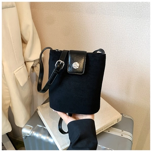 Detail view of black matte leather bucket bag with silver buckle and smooth top cover flap