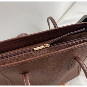 Detail of premium brown lychee texture leather tote bag with gold zipper closure