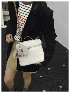 Détail du sac seau en peluche blanche avec bandoulière en cuir brun et pendentif lapin