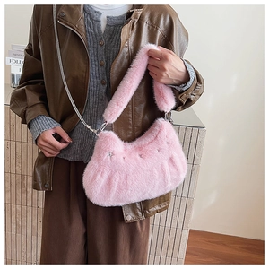 Detail of pink plush underarm bag with metal star studs and chain strap styling