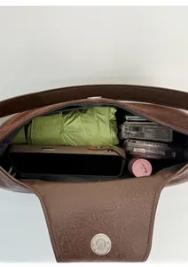 Top view of spacious interior of dark brown leather crossbody bag with daily essentials