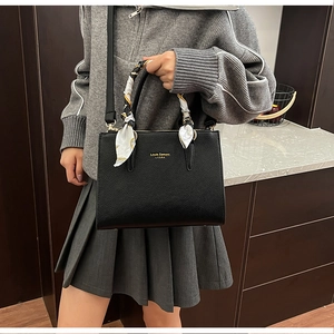 Close-up of black litchi grain leather tote bag with elegant scarf wrapped on handle