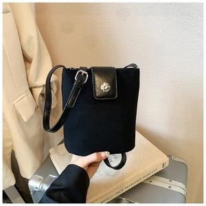 Detail of black suede and leather bucket bag with silver buckle and thin strap