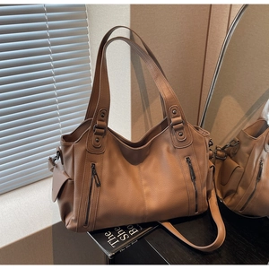 Close-up of khaki brown litchi pattern leather tote with decorative side zippers