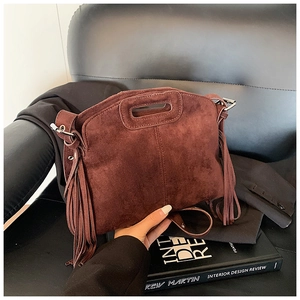 Macro detail of dark brown suede handbag featuring long fringe and cutout handle